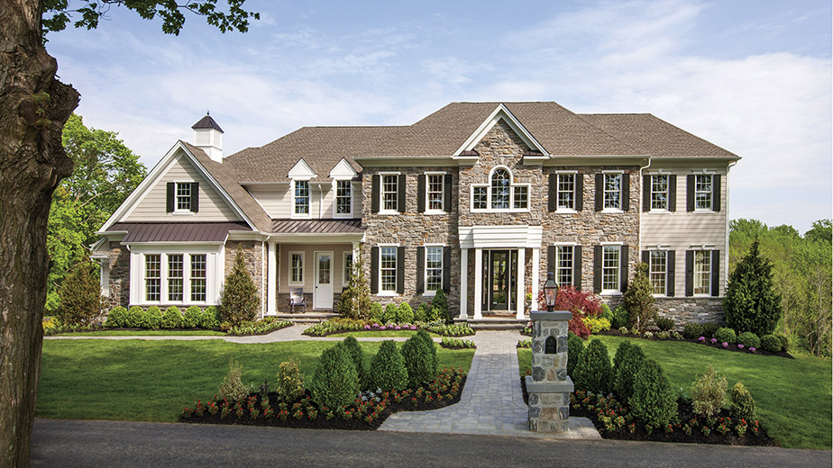 french colonial home with lots of windows and landscaping 