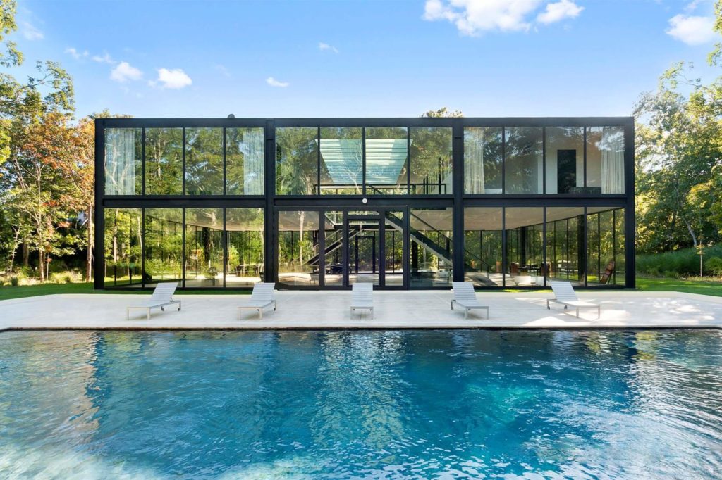 Glass House  with a pool in the foreground 