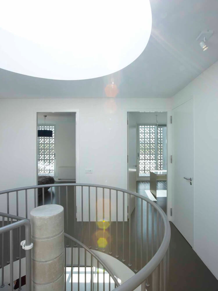 A spiral staircase in a white room with a skylight of W House VMX Architects