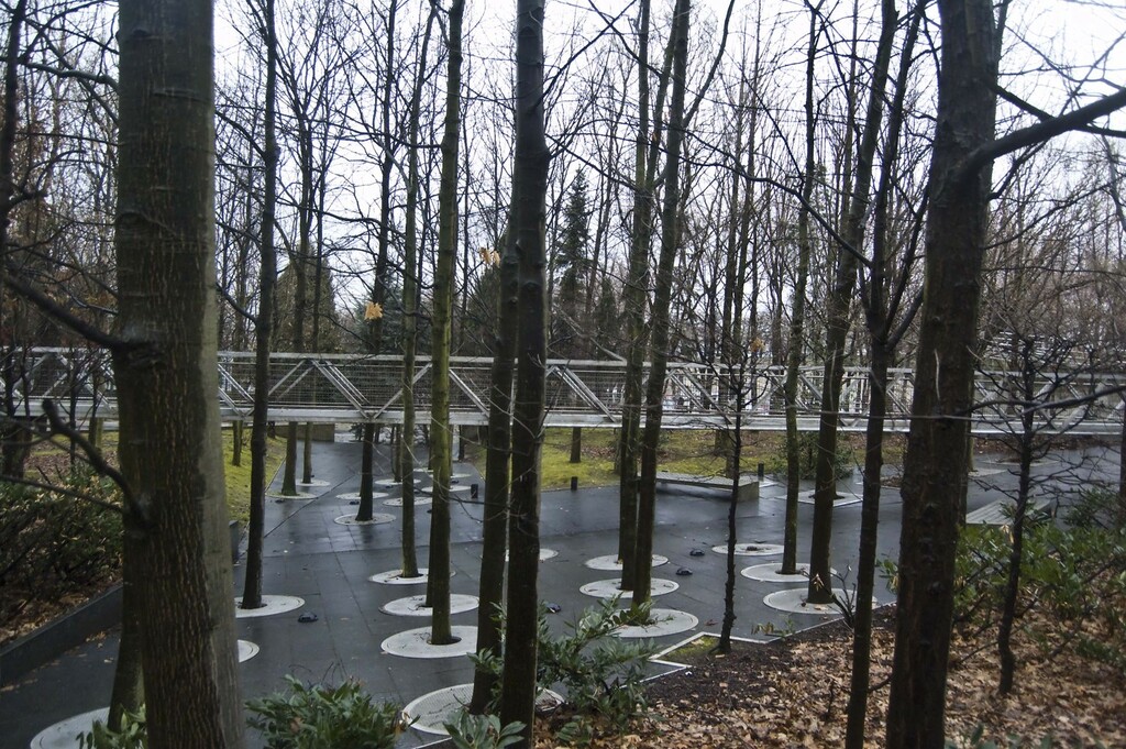 A park with trees and a bridge in the background
