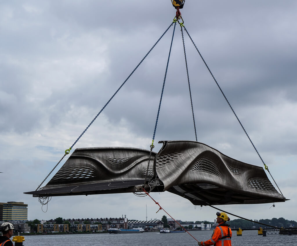 A crane is lifting a large piece of MX3D Smart Bridge