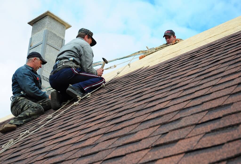 Three men working on the roof of a house
