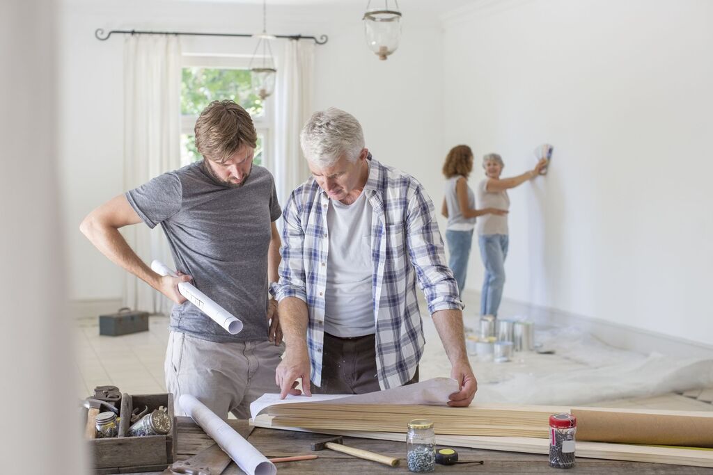 A couple of men standing next to each other in a room and look into Home Renovations plan
