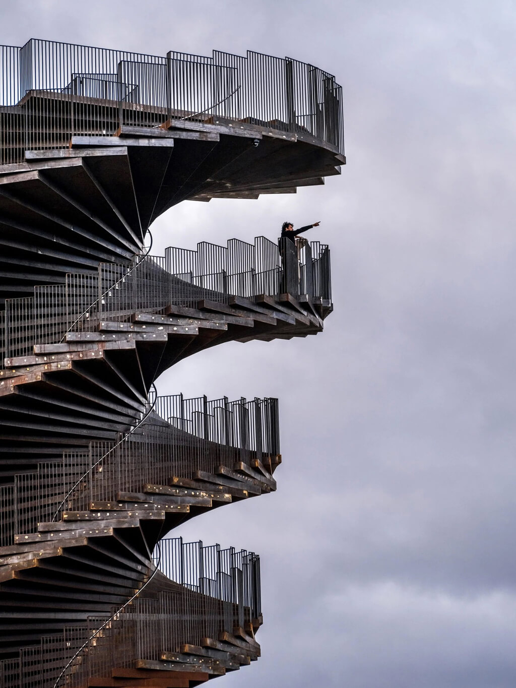 A man standing on a balcony next to 
marsk tower by bjarke ingels group's