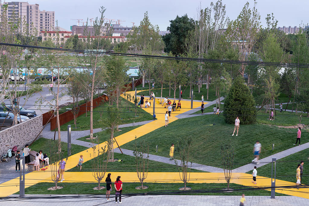 A group of people walking around a 
songzhuang micro community park by crossboundaries