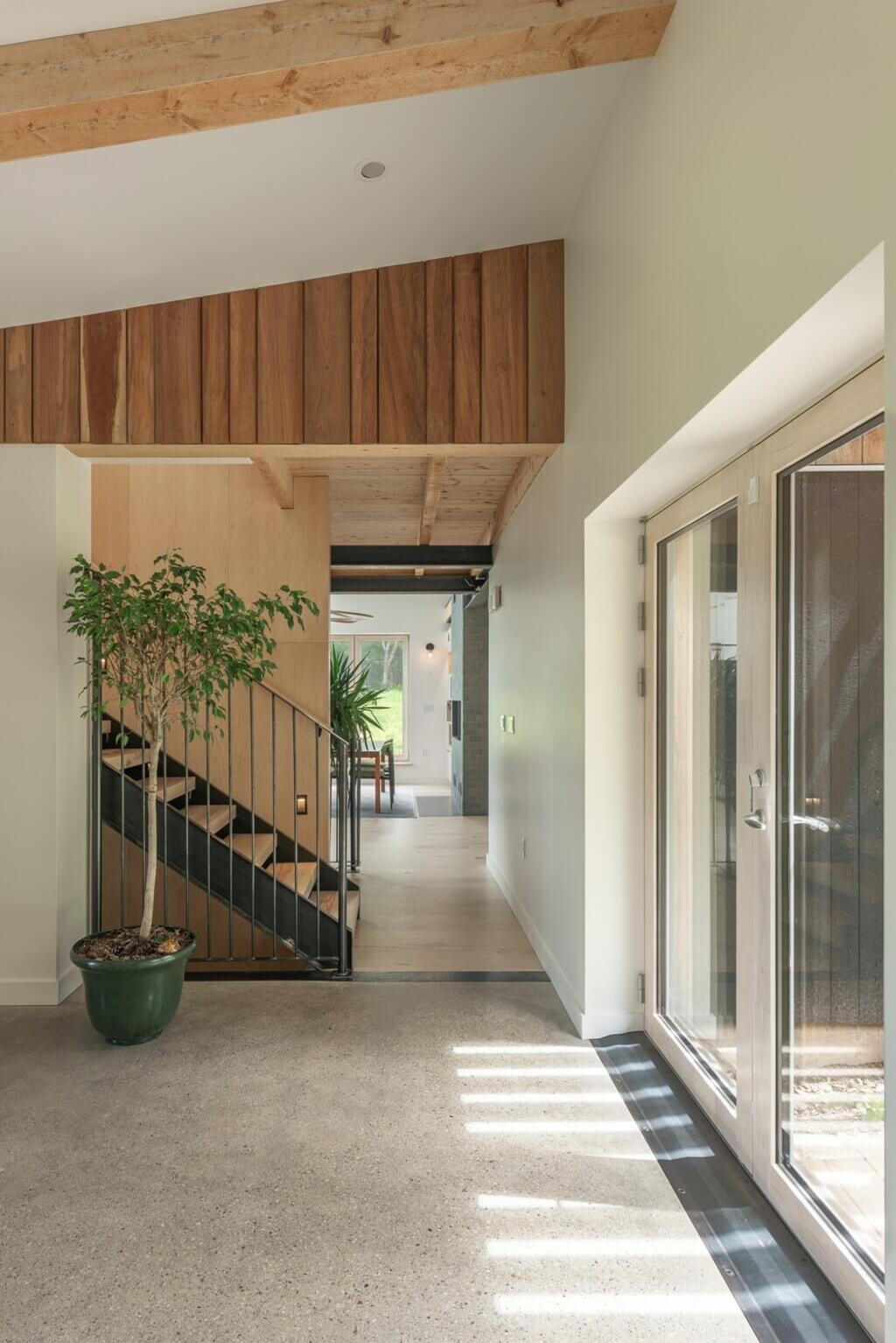 Two Rocks House Habit Studio long hallway with a plant in a pot next to a stair case
