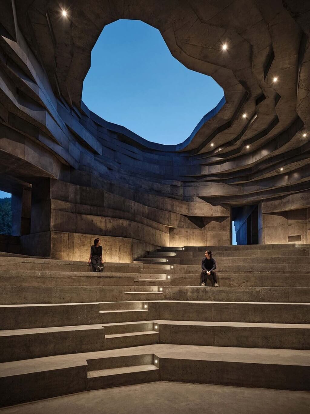 A couple of people that are sitting on some steps in Chapel of Sound by OPEN Architecture