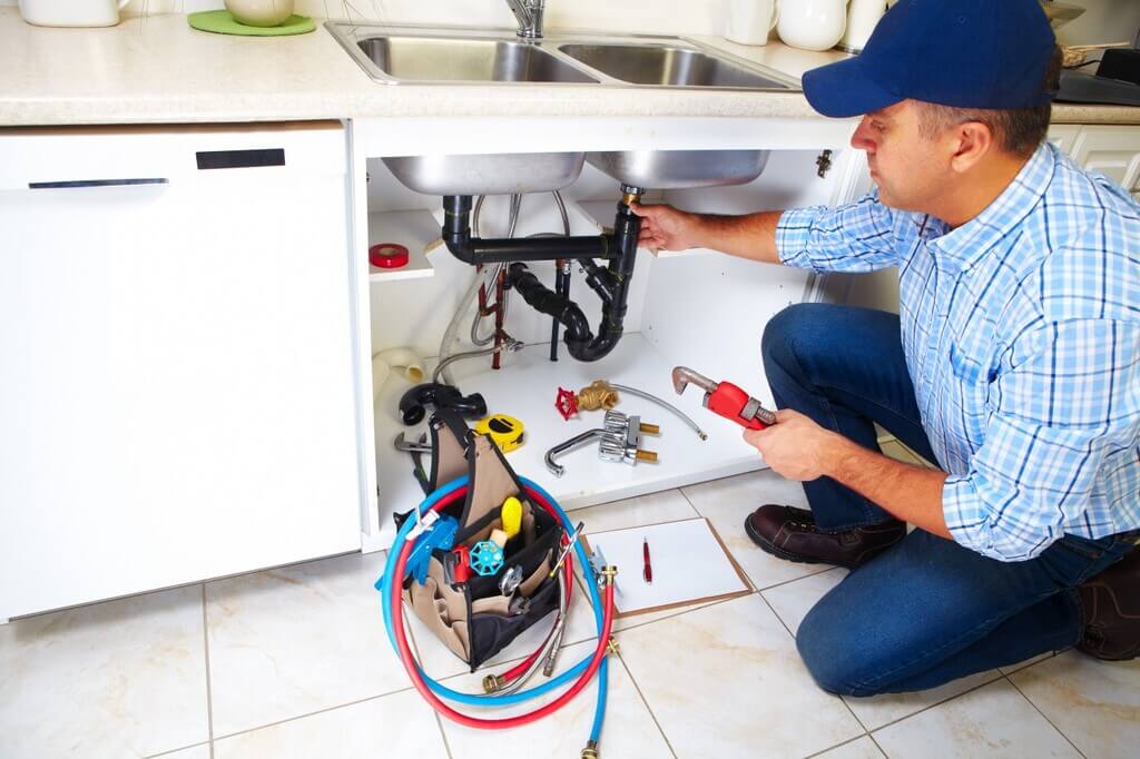 Professional Plumber fixing a sink in a kitchen
