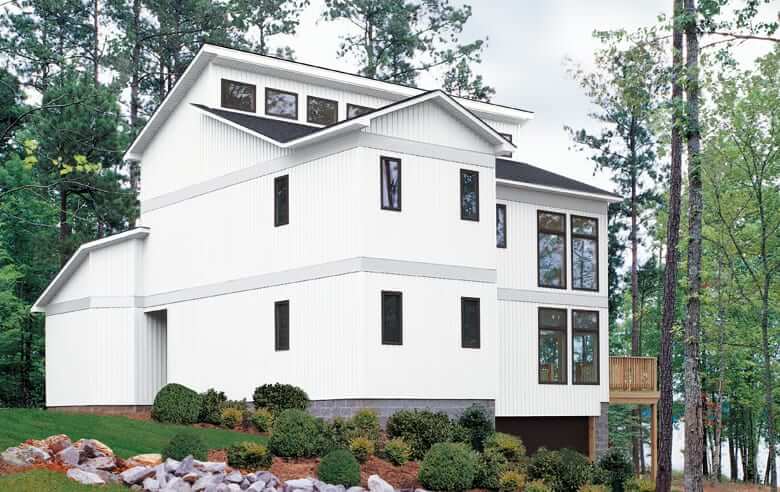 A large white house Board and Batten Siding in the middle of a forest