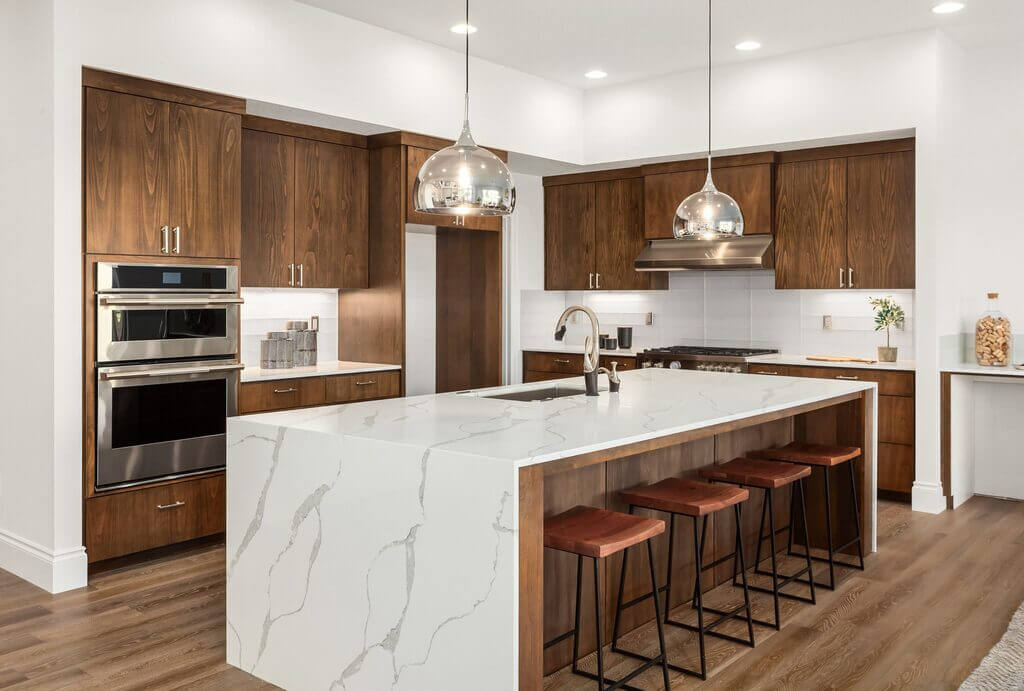 A kitchen with a marble island and wooden cabinets
