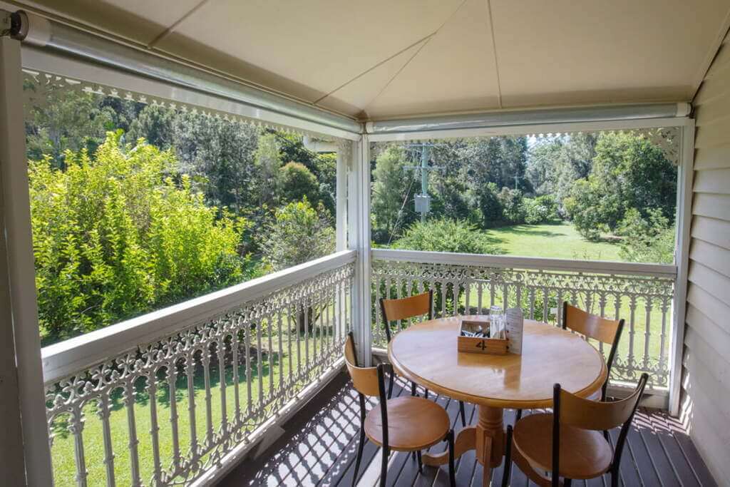 Queenslander homes porch with a table and chairs on it
