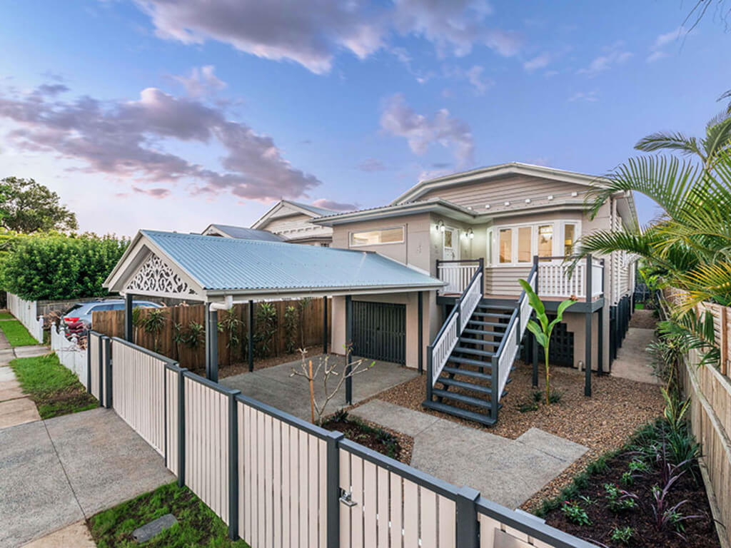 Queenslander homes with a white fence and steps leading to it
