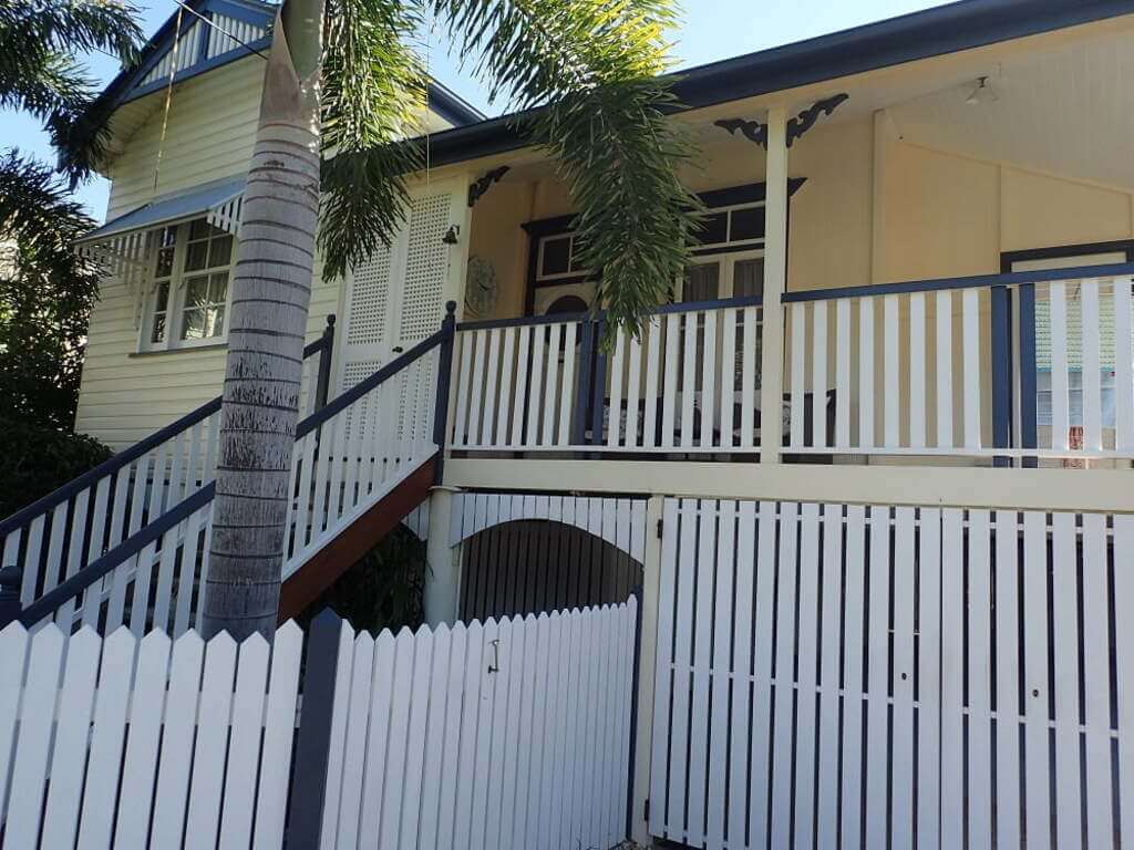 queenslander style home with a palm tree in front of it