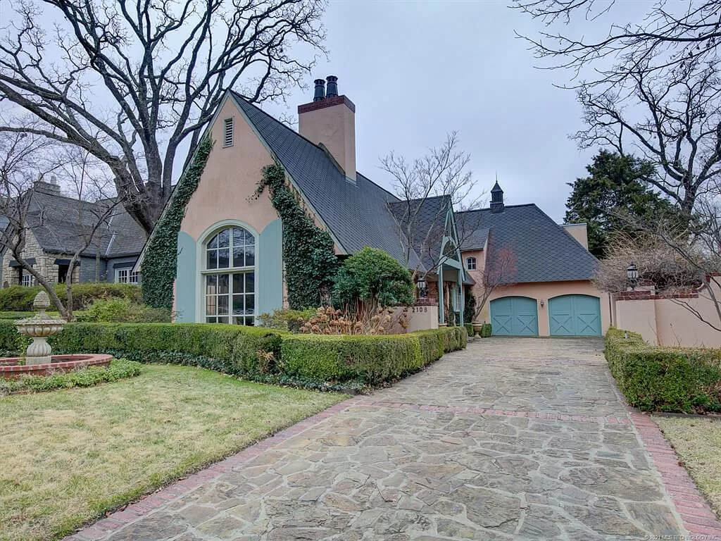 Storybook style homes with a driveway and a stone walkway in front of it 