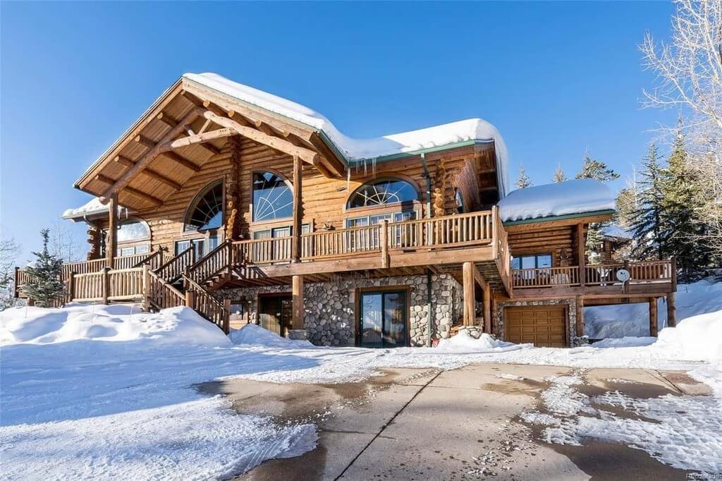 large log home with snow on the roof