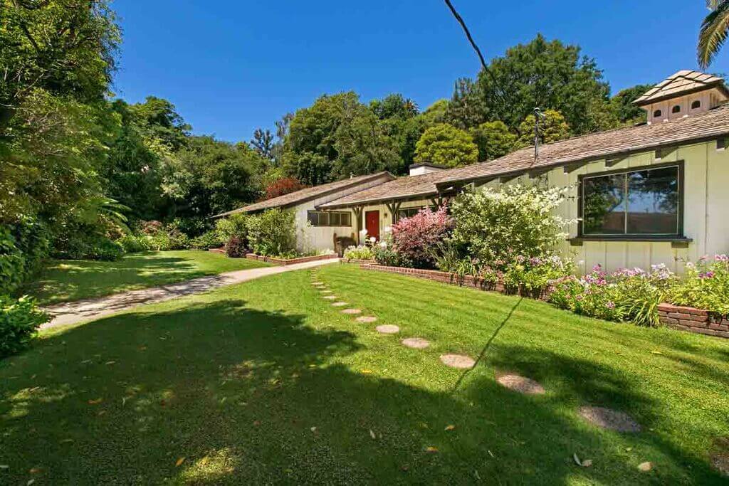 Ranch Style  house with a large lawn and trees in the background