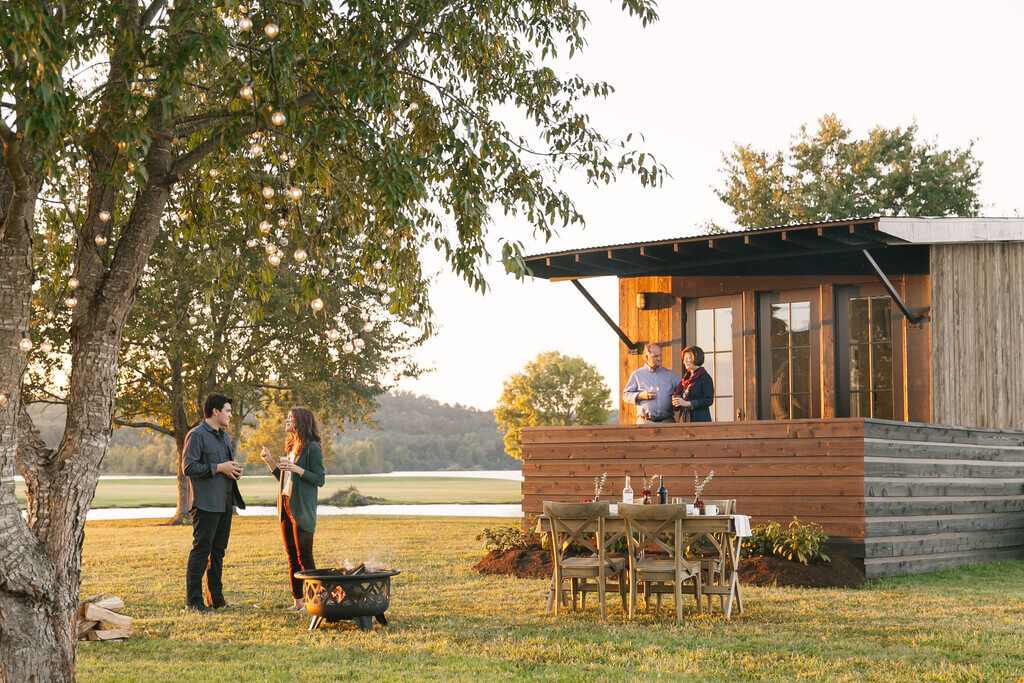 A group of people standing outside of a salt box house