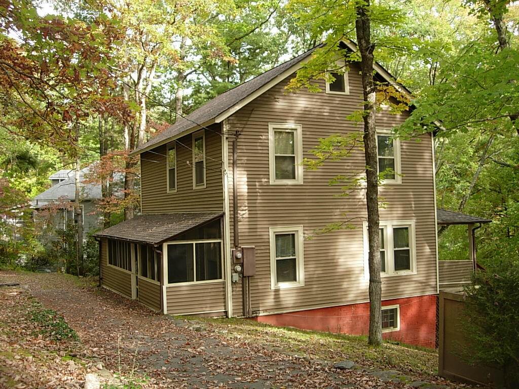 salt box style house in the middle of a wooded area