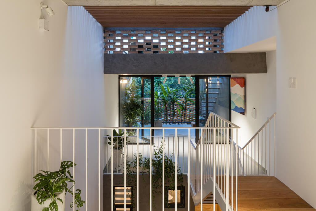 A staircase leading up to a balcony with a potted plant
