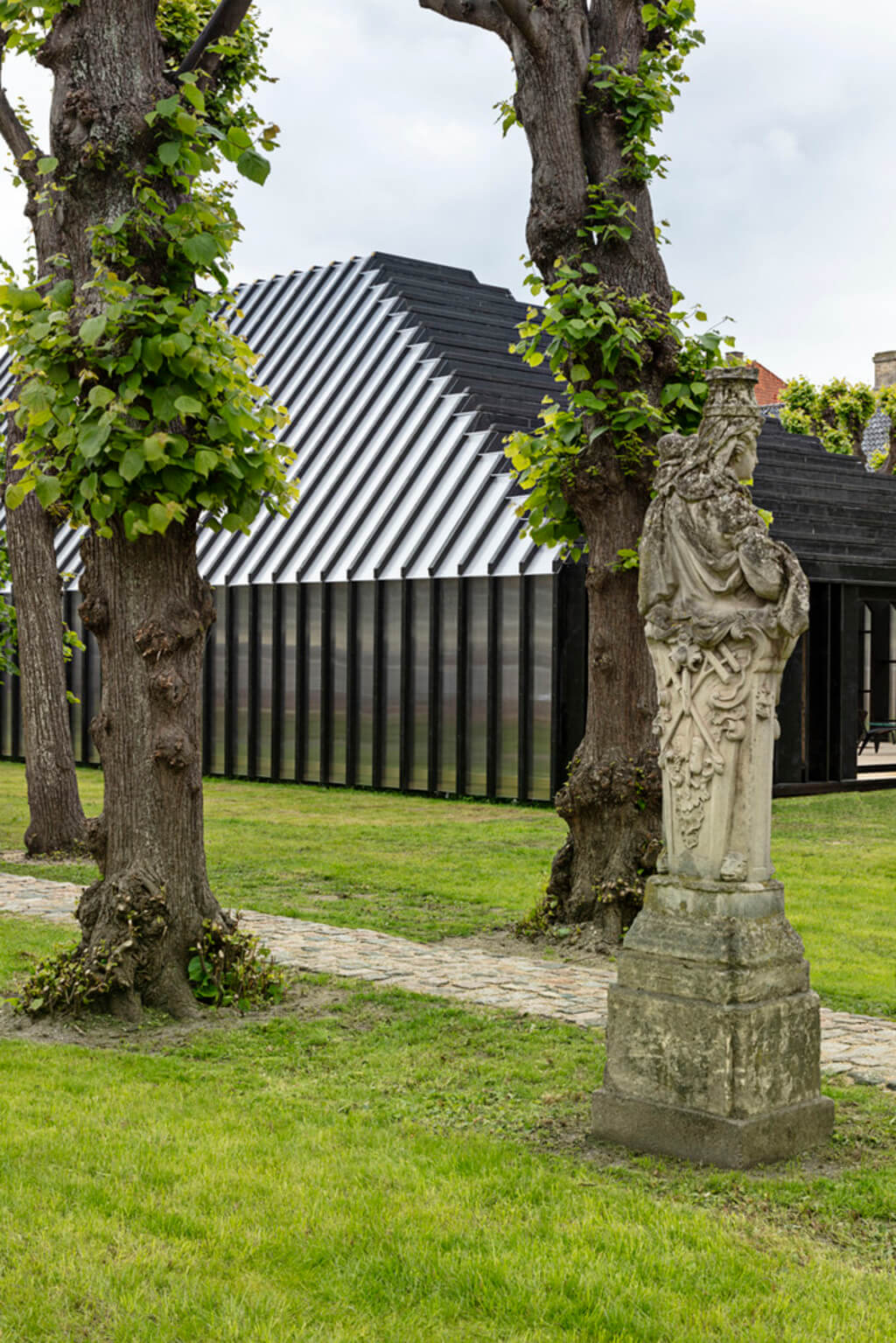 Fritz Hansen Pavilion and a statue in the middle of a grassy area
