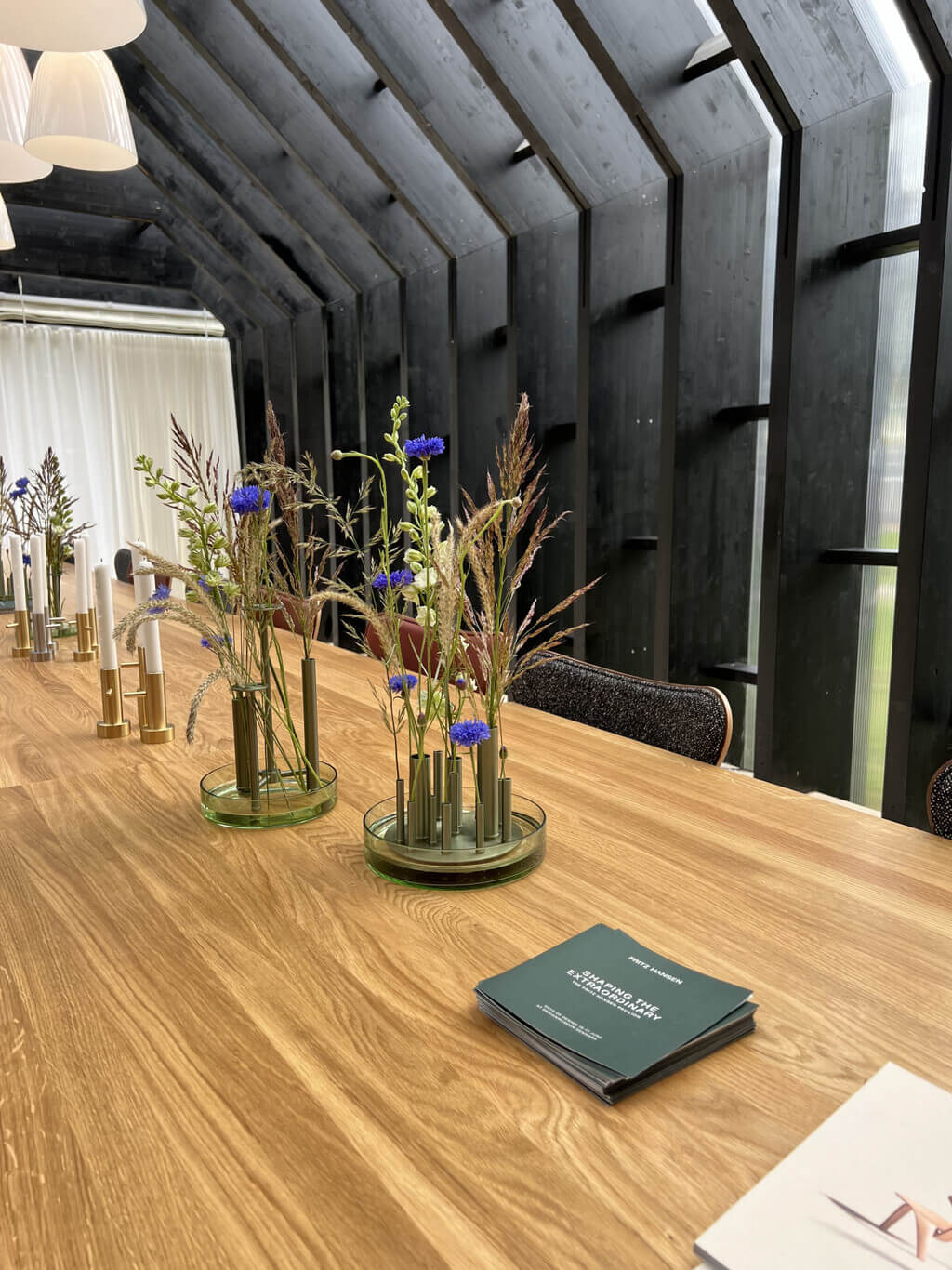 Fritz Hansen Pavilion with  wooden table topped with vases filled with flowers