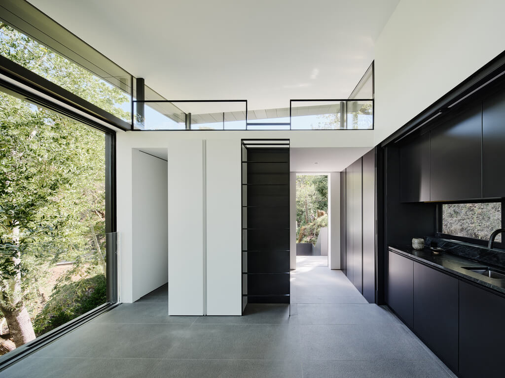 Suspension House long hallway with black cabinets and white walls
