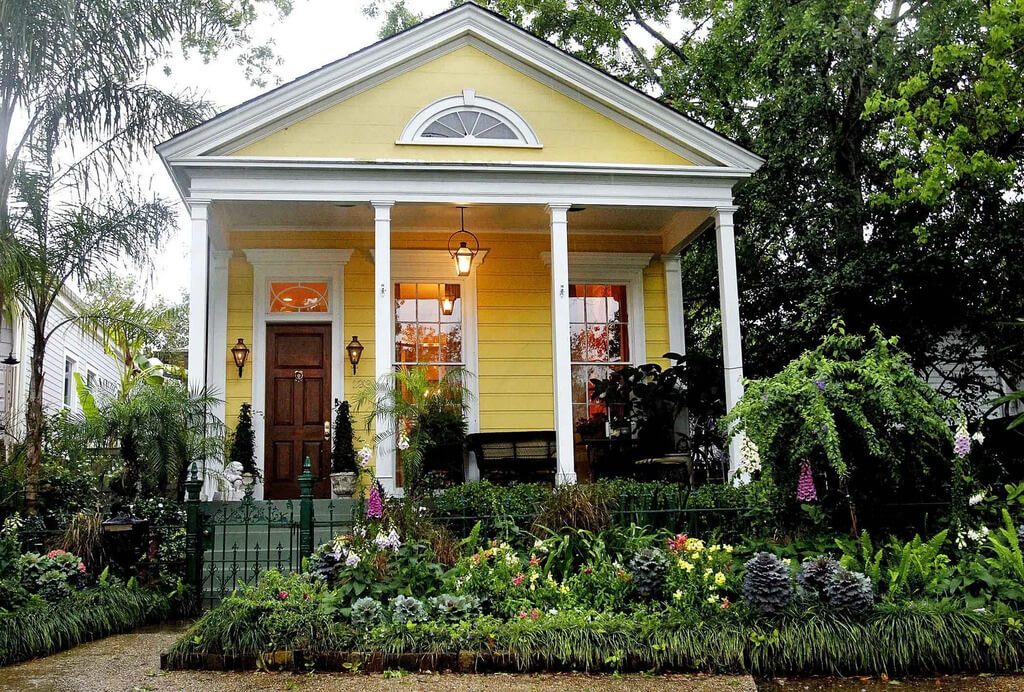 A yellow house with white trim and a porch shotgun style houses
