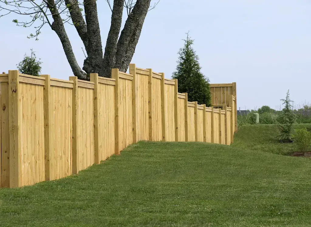 A wooden fence with a tree in the background
