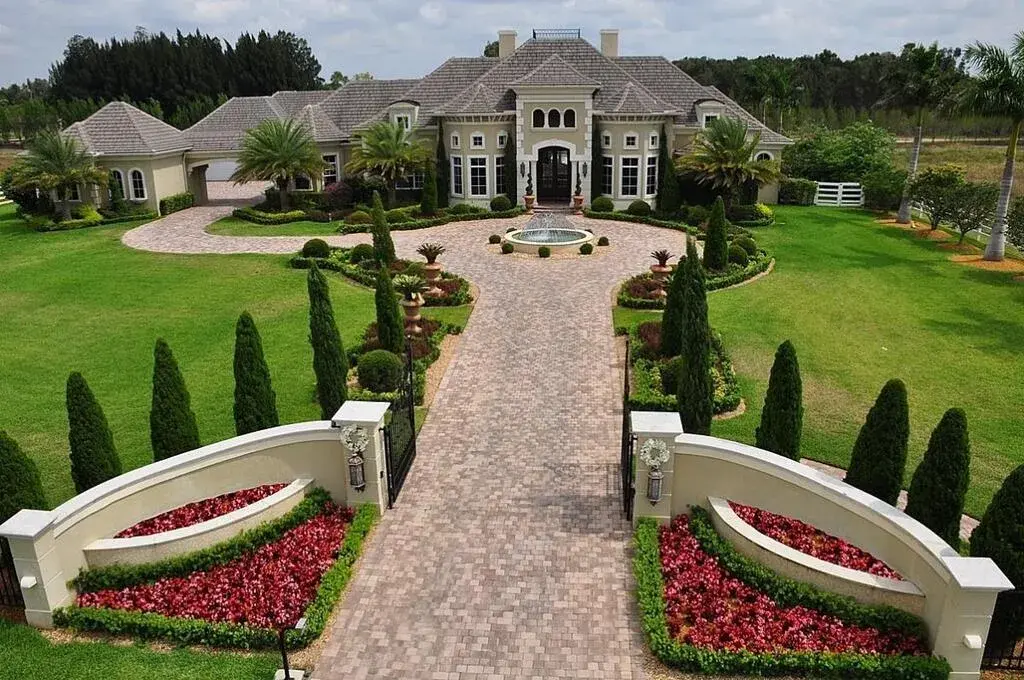 A large house with a driveway and a fountain
