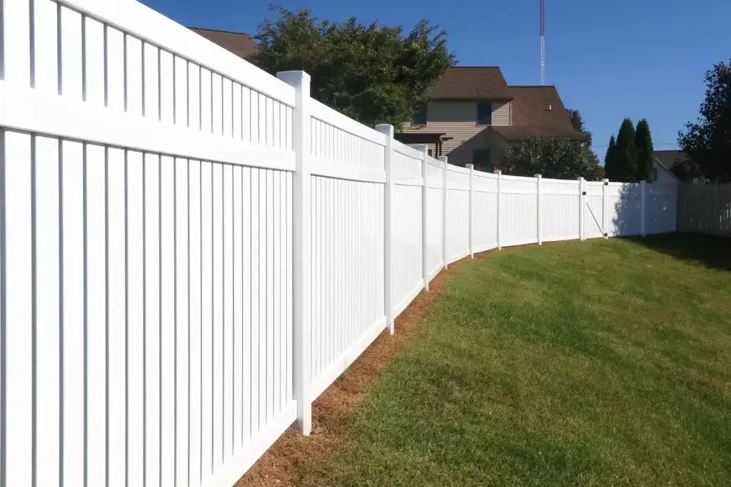 A white vinyl fence in front of a house
