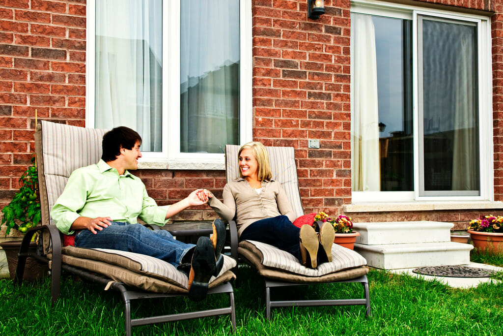 a man and a woman sitting on chairs in front of a house