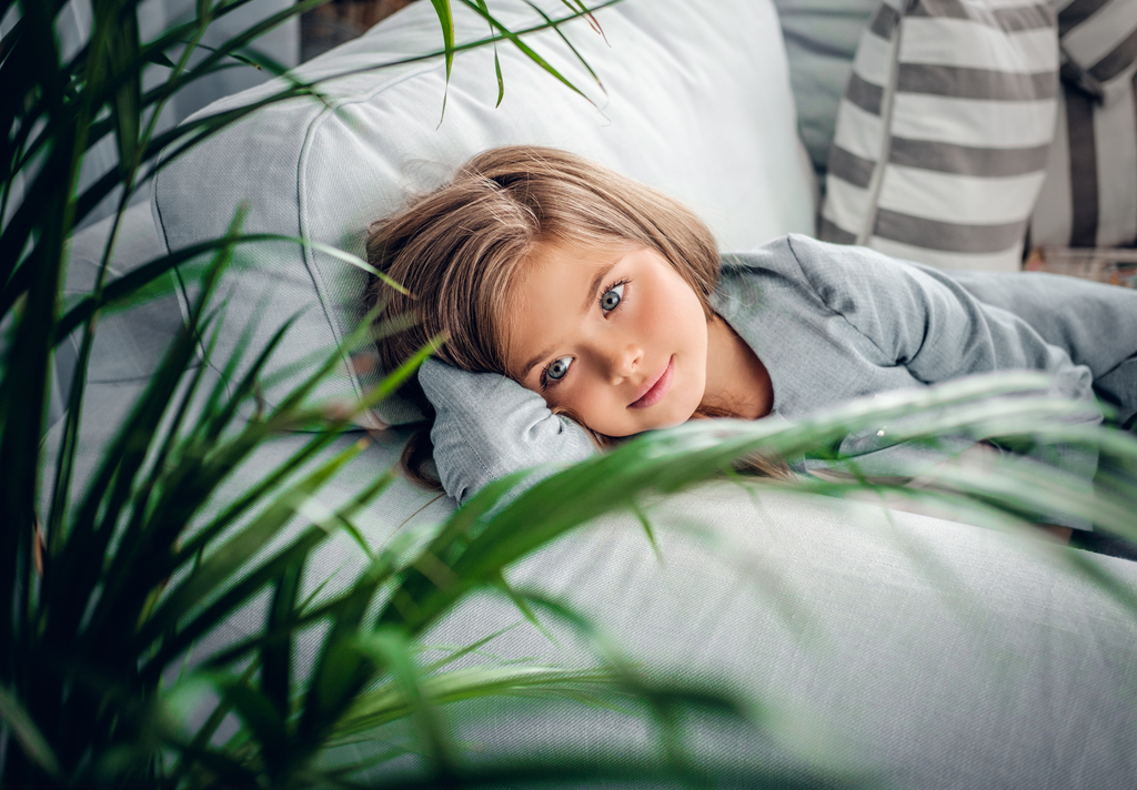 girl on a sofa in a living room with green plants
